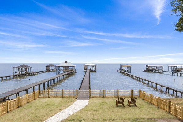 A waterfront property with multiple wooden docks extending into the water, connected by a central walkway. - Waterfront Bay View Retreat • High Tide Fairhope - Private Pier/Screened Porch (Fairhope)