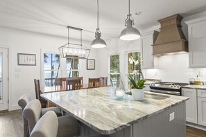 A modern kitchen with a marble island, pendant lighting, and a large stove. - Waterfront Bay View Retreat • High Tide Fairhope - Private Pier/Screened Porch (Fairhope)