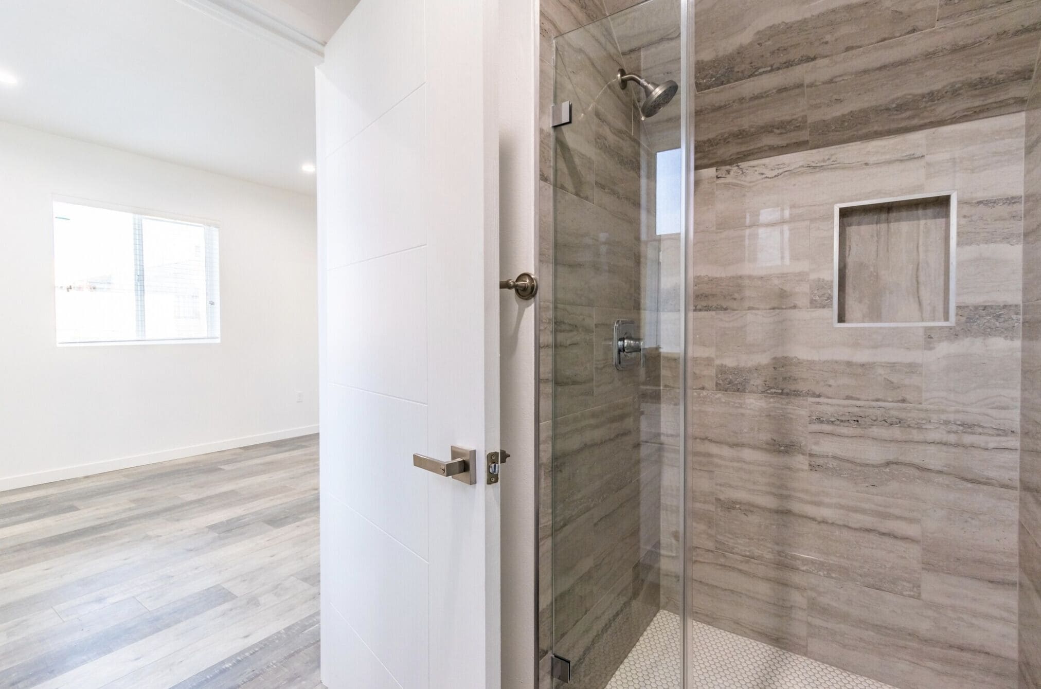 A modern bathroom with a glass shower enclosure, a white tiled shower area, and a wooden-textured wall.