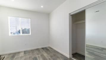 A room with a large window, a sliding closet door, and a wooden floor.