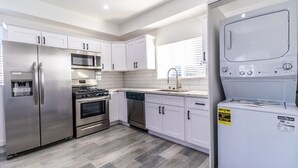 A modern kitchen with stainless steel appliances, white cabinetry, and a grey herringbone floor. - Boutique HomeStay (Los Angeles)