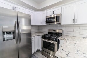 A modern kitchen with stainless steel appliances, white cabinets, and a marble countertop. - Boutique HomeStay (Los Angeles)