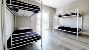 A room with two bunk beds, a large window, and a wooden floor. - Boutique HomeStay (Los Angeles)