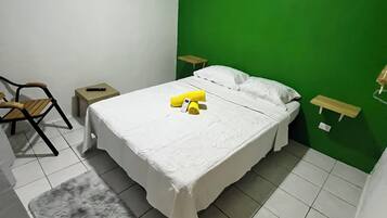 Una camera da letto con un letto, una sedia, un tavolino, un condizionatore d'aria e una parete verde decorativa.
