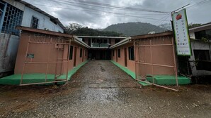 Un pasillo con literas, un tapete verde en la entrada y un letrero.