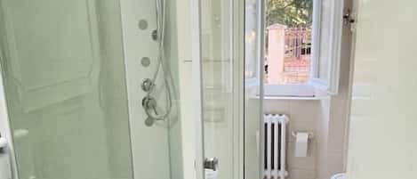 A modern bathroom with a glass-enclosed shower, a sink, and a radiator.