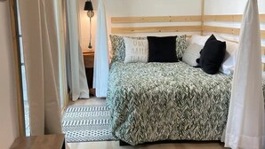 A bedroom with a bed, a nightstand, a lamp, and a window with curtains. - Lake Front Cottage on Trooper Lake, Troy Hill Ont (Tory Hill)