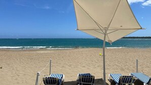 A beach with a canopy and striped lounge chairs. - Pool Viewapartment at thebeach (Puerto Plata Province)