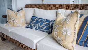 A wicker sofa with white cushions and decorative pillows. - Pool Viewapartment at thebeach (Puerto Plata Province)