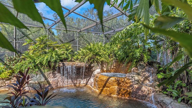 Ein tropischer Garten im Innenbereich mit Wasserfall und Pool.