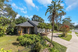 A residential house with a front porch, surrounded by lush greenery and a well-maintained lawn.