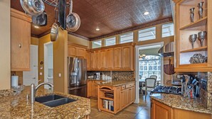 Eine Küche mit Granit Arbeitsplatten, Holzschränken, einem Edelstahl-Kühlschrank und einem eingebauten Backofen.