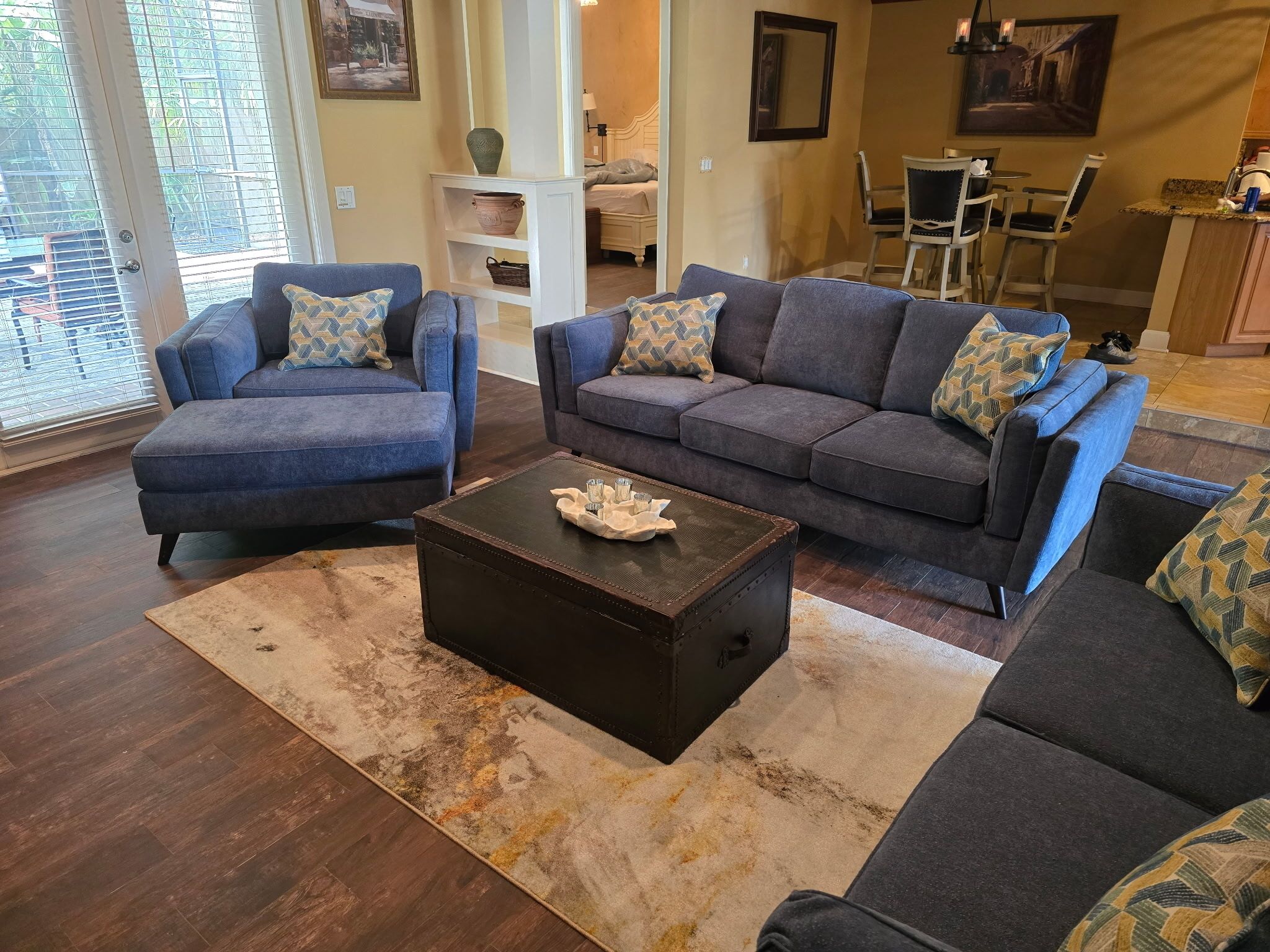 A living room with two blue sofas, a dark wooden coffee table, and a beige rug.
