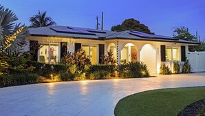 A modern house with a covered porch, solar panels, and a well-maintained garden. - The Vacation Getaway (Delray Beach)