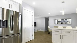 A modern kitchen with stainless steel appliances, white cabinetry, and a wooden floor. - The Vacation Getaway (Delray Beach)