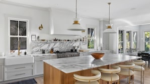 Una cocina moderna con una isla grande, encimeras de mármol y taburetes de bar.