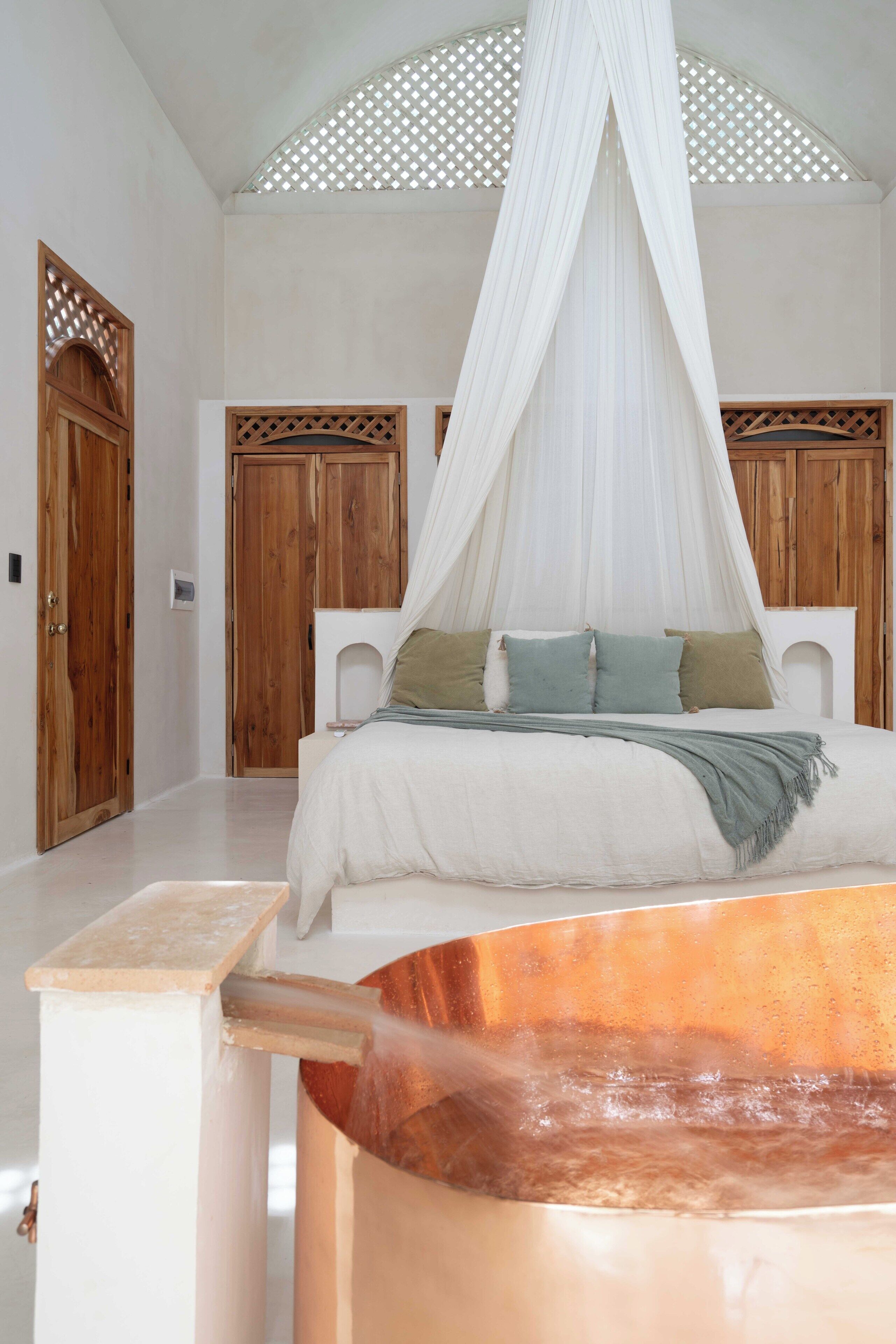 Una camera da letto con un letto grande, porte in legno e una vasca idromassaggio.