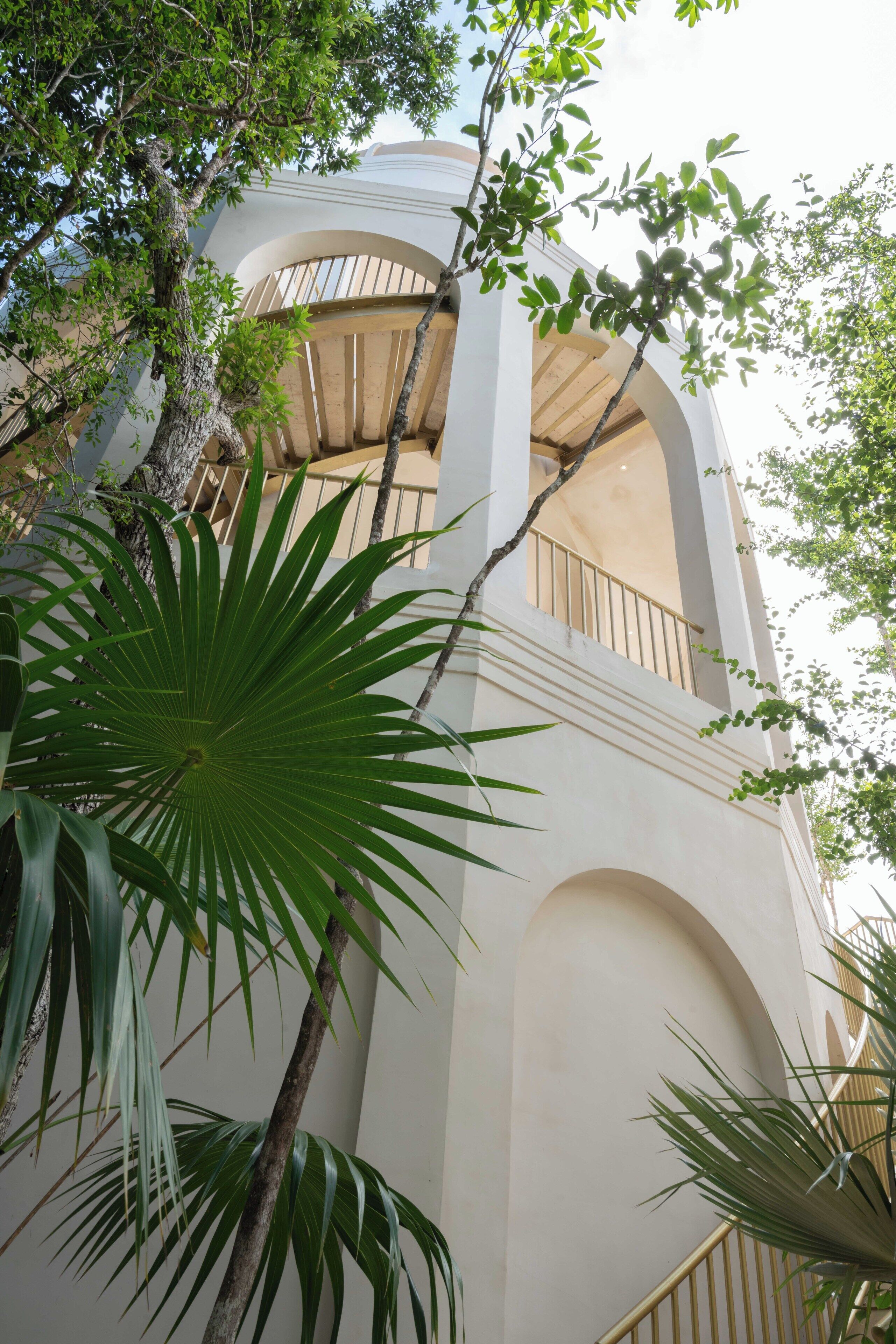 A building with arched balconies and a palm tree in the foreground.