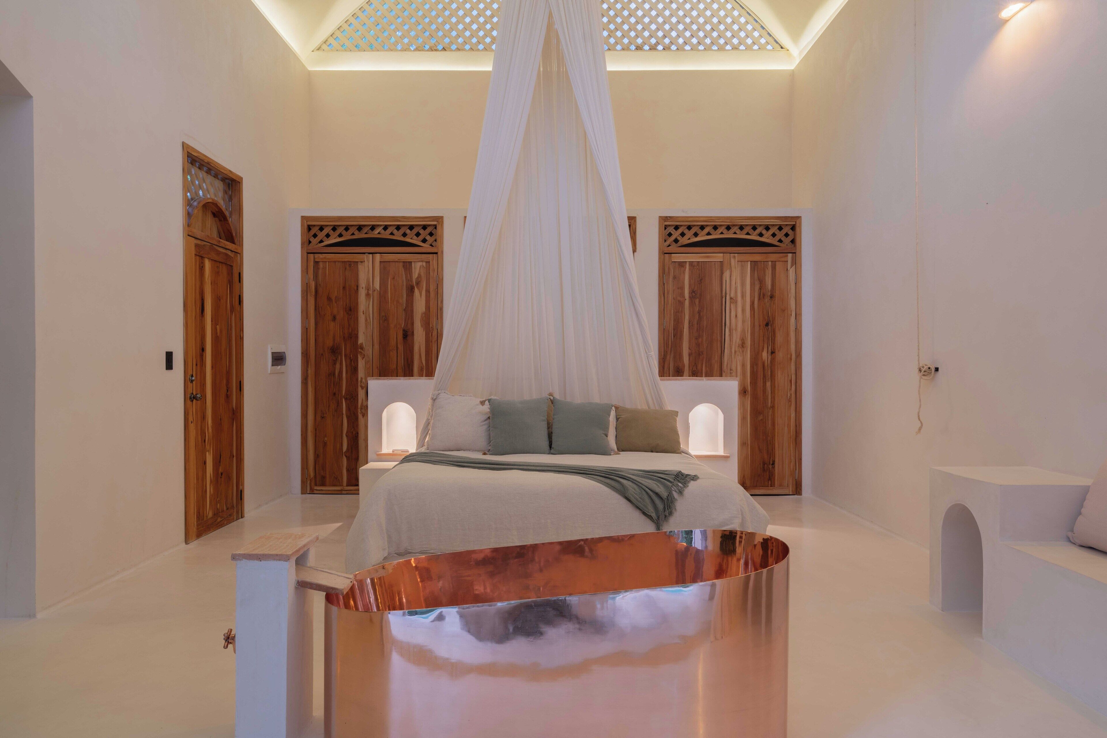 Une chambre à coucher avec un lit à baldaquin, des portes en bois et un mur blanc.