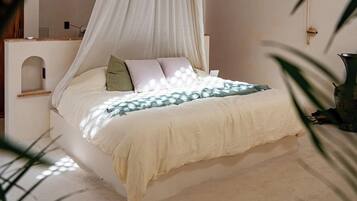 Una cama con dosel, una mesita de noche y una planta en maceta.