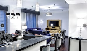En moderne stue med en blå sofa, et fladskærms-TV og et spiseområde med en bar.