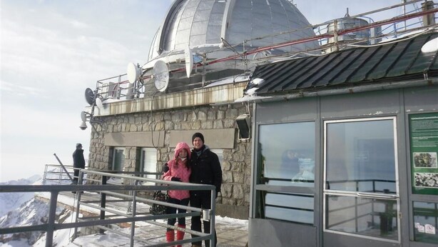 Un edificio de piedra con una gran estructura en forma de cúpula, una barandilla metálica y cielo despejado.