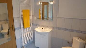 Un baño con lavamanos blanco, un espejo, un inodoro y un perchero para toallas.