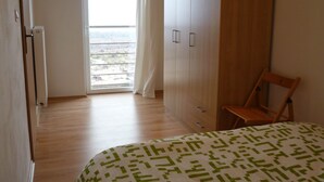 Un dormitorio con cama, armario de madera y una silla.