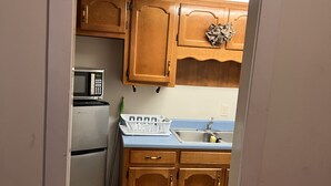 A kitchen with wooden cabinets, a microwave, a refrigerator, and a sink. - Joy Apartment #3 centrally located.  (Anniston)