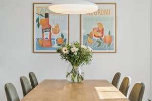 A dining table with chairs, a vase with flowers, and two framed posters on the wall. - Cozy central house near the sea (Brenderup)