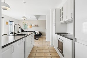 A modern kitchen with white cabinetry, a black countertop, and a central island.