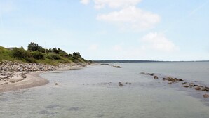 A calm beach with clear water, pebbles, and a distant shoreline. - Cozy, central house near the sea (Brenderup)