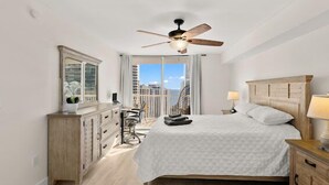 Ein Hotelzimmer mit Bett, Schreibtisch, Stuhl, Deckenventilator und Blick auf die Stadt.
