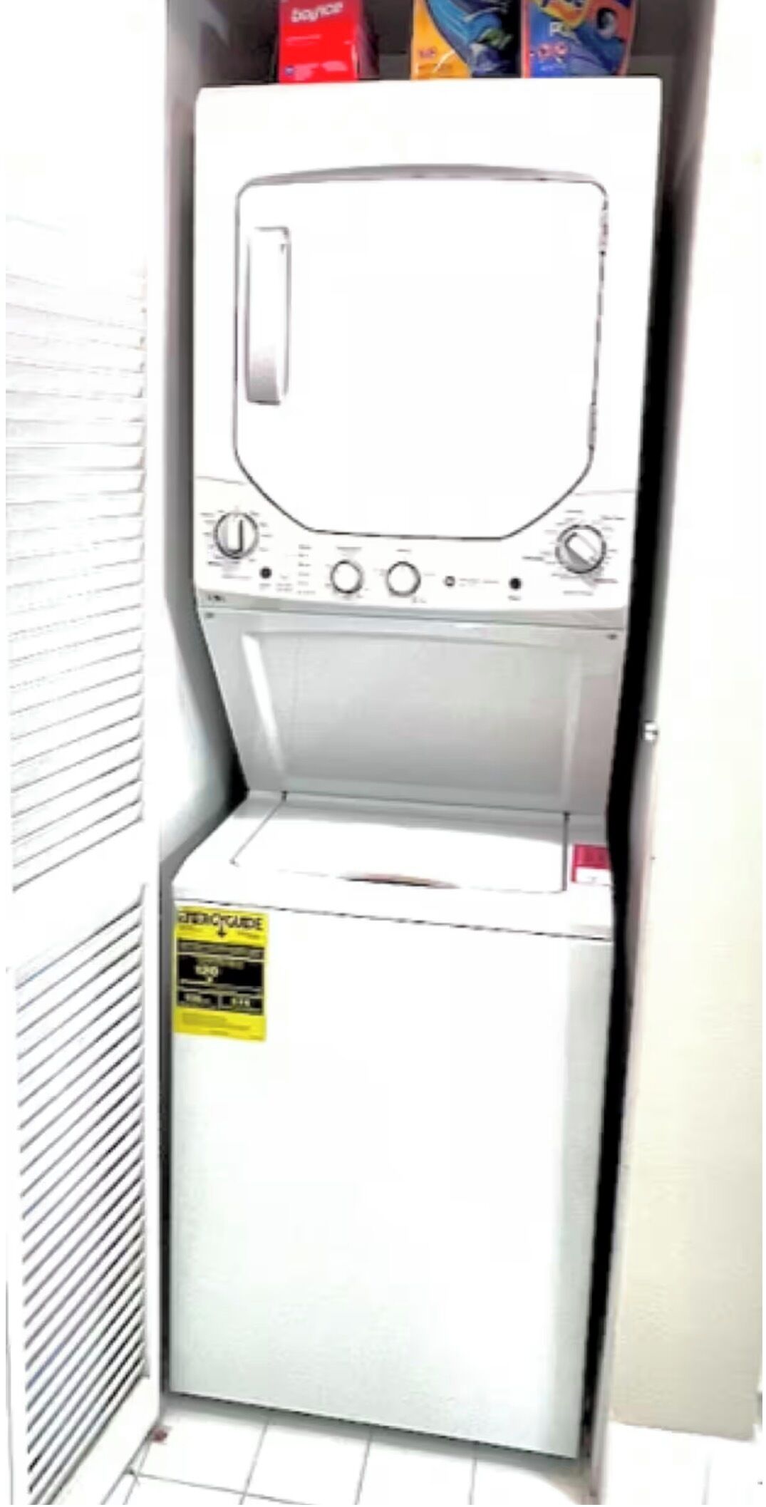 A white washing machine with a control panel and a yellow sticker on the door.