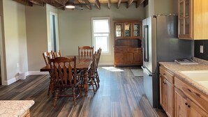 A spacious kitchen with wooden cabinets, a dining table with chairs, and a built-in refrigerator.