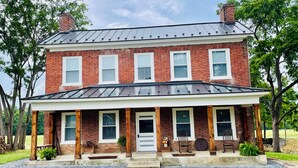 A two-story brick house with a covered porch and a metal roof.