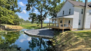 A house with a wooden deck and a pond in the backyard.