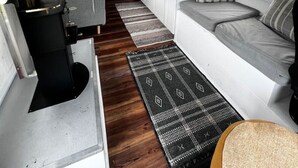 A compact, well-lit interior with a kitchenette, seating area, and a view through the windows.