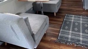 A compact, modern RV interior with a dining area, seating, and a kitchen.