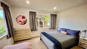 Un dormitorio con cama, mesita de noche, lámpara y ventana con cortinas.