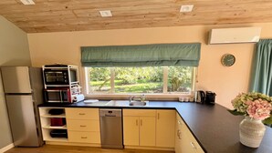 Una cocina moderna con lavavajillas incorporado, refrigerador de acero inoxidable y ventana con vista a la vegetación.