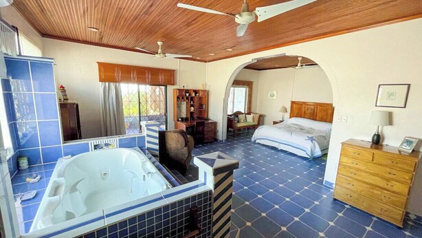 Ein geräumiges Schlafzimmer mit einem großen Bett, einem eigenen Badezimmer mit einer Badewanne und einem begehbaren Kleiderschrank.