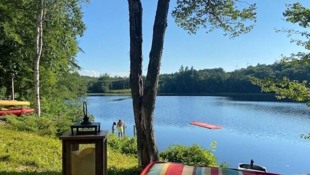A lakeside view with a picnic table, a lamp, and a canoe. - Direct Waterfront, Year-Round, A-Frame Cabin (Antrim)