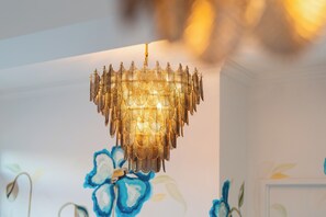 A stunning chandelier with a unique design hangs from the ceiling, complemented by a floral-patterned wall.