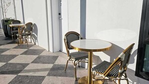 Un área de estar al aire libre con piso a cuadros, una mesa redonda y sillas de mimbre.