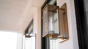 Un primer plano de una lámpara de pared con una pantalla de cristal transparente y detalles en latón.