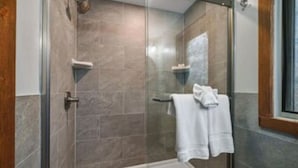 A glass-enclosed shower area with a white bathtub, tiled walls, and a towel rack with a white towel. - Ski Side Getaway < 1 Mile From Mountain  (Tannersville)