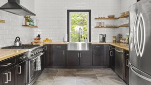A modern kitchen with dark cabinets, stainless steel appliances, and a view through a window.