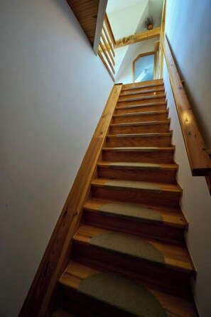 Een houten trap met een leuning, die leidt naar een verdieping.