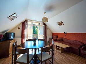 Un salón acogedor con una mesa de comedor de madera, un sofá rojo y un televisor sobre un mueble de madera.